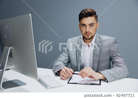 businessmen in a gray suit sits in front of a computer technologies 92497721