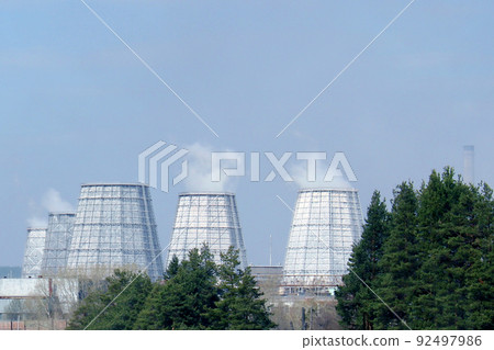 Large factory chimneys in an industrial area against the backdrop of a forest. Environmental pollution. Ecological concept.. 92497986