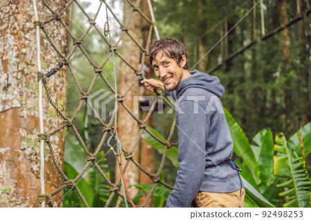 strong young men in a rope park on the wood background strong young men in a rope park on the wood background 92498253