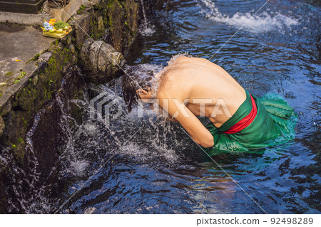 Man in holy spring water temple in bali. The temple compound consists of a petirtaan or bathing structure, famous for its holy spring water Man in holy spring water temple in bali. The temple compound consists of a petirtaan or bathing structure, famous for its holy spring water 92498289