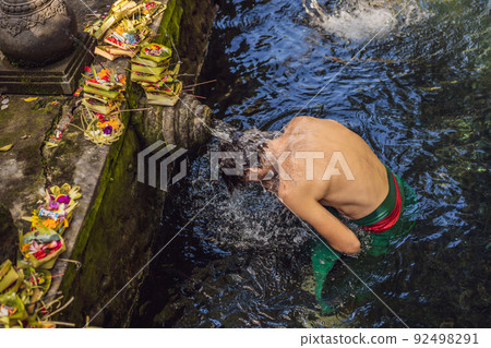 Man in holy spring water temple in bali. The temple compound consists of a petirtaan or bathing structure, famous for its holy spring water Man in holy spring water temple in bali. The temple compound consists of a petirtaan or bathing structure, famous for its holy spring water 92498291