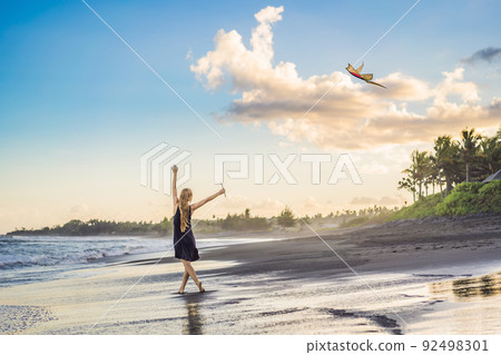 A young woman launches a kite on the beach. Dream, aspirations, future plans 92498301