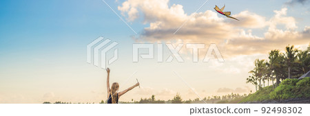 A young woman launches a kite on the beach. Dream, aspirations, future plans BANNER, LONG FORMAT 92498302