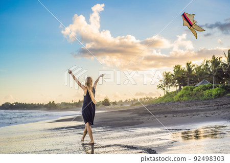 A young woman launches a kite on the beach. Dream, aspirations, future plans A young woman launches a kite on the beach. Dream, aspirations, future plans 92498303