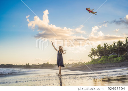 A young woman launches a kite on the beach. Dream, aspirations, future plans 92498304