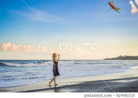 A young woman launches a kite on the beach. Dream, aspirations, future plans 92498310