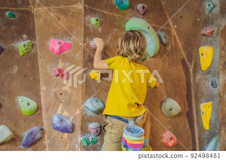 little boy climbing a rock wall in special boots. indoor 92498481