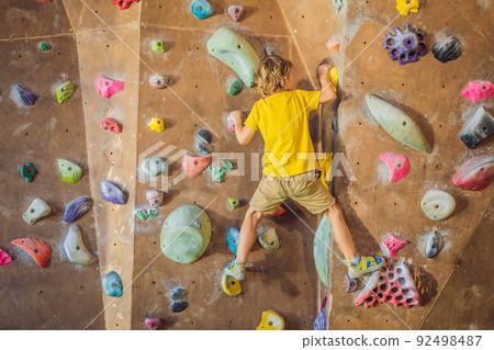 little boy climbing a rock wall in special boots. indoor 92498487