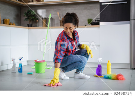 Glad millennial african american woman housewife in rubber gloves wash floor with cleaning supplies 92498734
