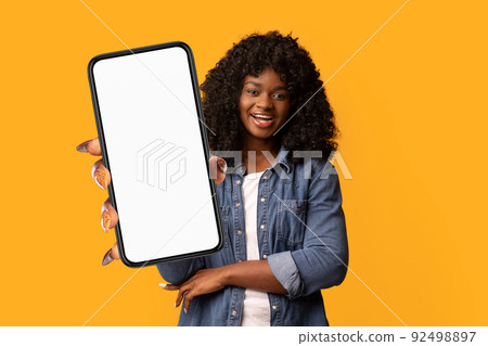 Happy beautiful black woman on yellow background, showing smartphone Happy beautiful black woman on yellow background, showing smartphone 92498897