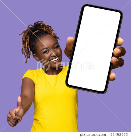 Joyful african american woman showing celll phone and thumb up 92498925