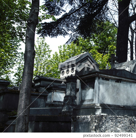 Tombstones in cemetery at dusk, gothic style crosses Paris close up 92499141