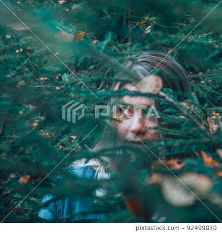The girls gaze through the foliage in the woods. 92499830