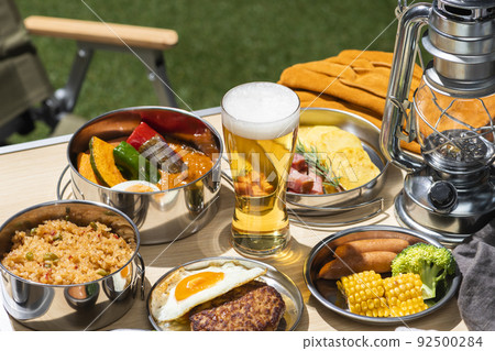 Meals and beer lined up at an outdoor camping table 92500284