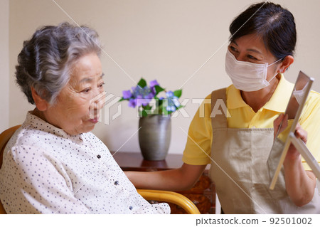 Elderly woman looking in the mirror with makeup Elderly woman looking in the mirror with makeup 92501002