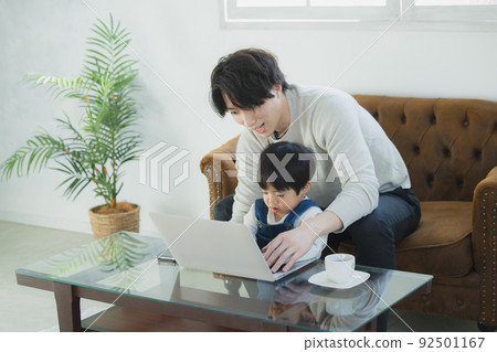 Dad and little boy looking at a computer Dad and little boy looking at a computer 92501167