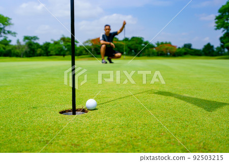 Golfer putt golf ball into hole on the green at golf course Golfer putt golf ball into hole on the green at golf course 92503215
