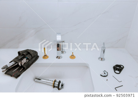 As part of his work, the plumber assembles, installs, and adjusts the water faucet in the bathroom. 92503971
