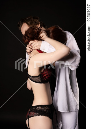 Sensual BDSM couple hugging with collar in dark 92505067