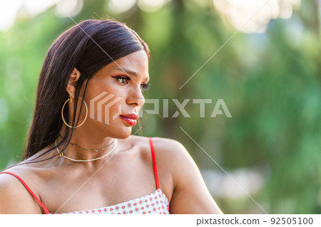 Transgender woman looking aside with worried expression outdoors Transgender woman looking aside with worried expression outdoors 92505100