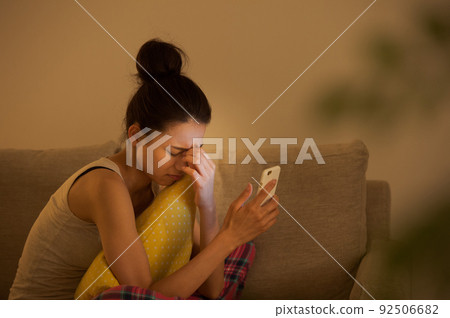 A woman watching a smartphone on a sofa 92506682