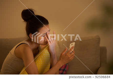 A woman watching a smartphone on a sofa 92506684