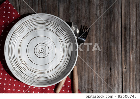 Empty ceramic white plate on a rustic loft wooden table. Kitchen food background with copy space with mockup for menu or recipe top view 92506743