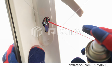 Handyman applying lubricate for lock of plastic window 92506980