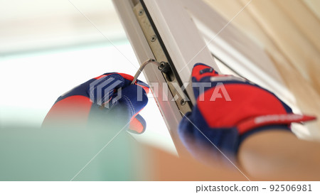 Male hands in gloves adjusting locks of windows with special tool Male hands in gloves adjusting locks of windows with special tool 92506981