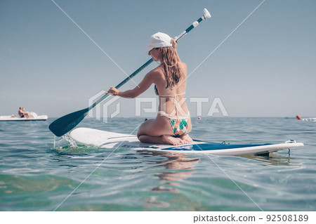 SUP Stand up paddle board. Young woman sailing on beautiful calm sea with crystal clear water. The concept of an summer holidays vacation travel, relax, active and healthy life in harmony with nature. 92508189