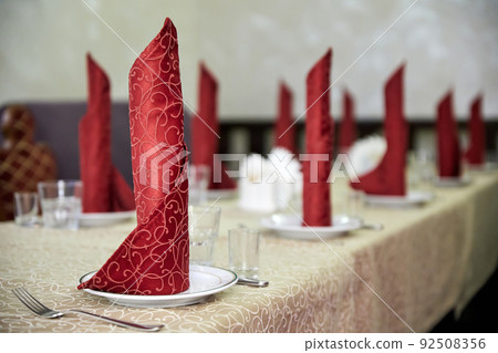 Served banquet table in a cafe with red napkins Served banquet table in a cafe with red napkins 92508356