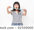 Cute girl 6 year old holding a blue slime and exited. Studio isolated on white background. 92509000