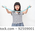 Cute girl 6 year old holding a blue slime and exited. Studio isolated on white background. 92509001