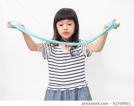 Cute girl 6 year old holding a blue slime and exited. Studio isolated on white background. Cute girl 6 year old holding a blue slime and exited. Studio isolated on white background. 92509001