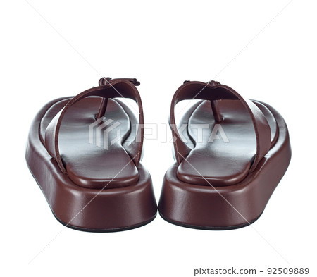 Beautiful pair of brown flip-flops made of genuine leather with stripes-straps on top and a massive high sole. Rear view. The trend of the season. Beautiful pair of brown flip-flops made of genuine leather with stripes-straps on top and a massive high sole. Rear view. The trend of the season. 92509889