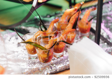 Large table with snacks of different types at a party with creative disco lighting. Large table with snacks of different types at a party with creative disco lighting. 92509936