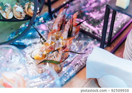 Large table with snacks of different types at a party with creative disco lighting. Large table with snacks of different types at a party with creative disco lighting. 92509938