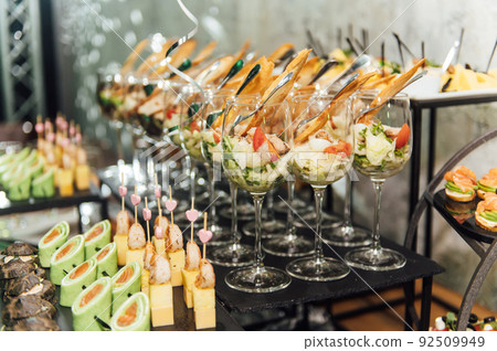 Large table with snacks of different types at a party with creative disco lighting. 92509949