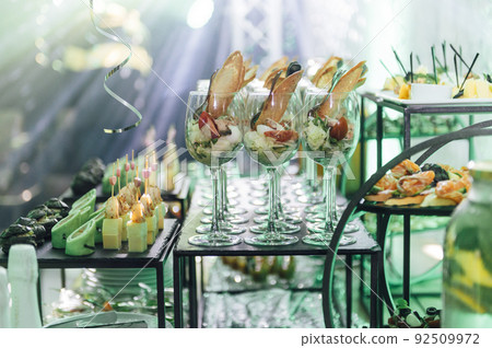Large table with snacks of different types at a party with creative disco lighting. 92509972