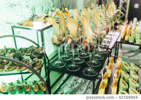 Large table with snacks of different types at a party with creative disco lighting. 92509984