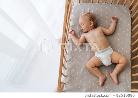 Upper view copy space portrait of cute baby sleeping in his bed lying on back watching sweet dreams 92510096