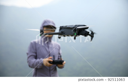 Woman remotel control a flying drone in spring forest 92511063