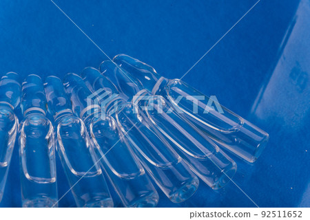 Glass medical ampoule vial for injection. Medicine is liquid sodium chloride with of aqueous solution in ampulla. Close up. Bottles ampule multicolor. Glass medical ampoule vial for injection. Medicine is liquid sodium chloride with of aqueous solution in ampulla. Close up. Bottles ampule multicolor. 92511652