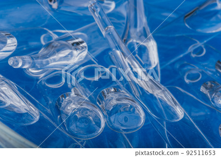 Glass medical ampoule vial for injection. Medicine is liquid sodium chloride with of aqueous solution in ampulla. Close up. Bottles ampule multicolor. Glass medical ampoule vial for injection. Medicine is liquid sodium chloride with of aqueous solution in ampulla. Close up. Bottles ampule multicolor. 92511653