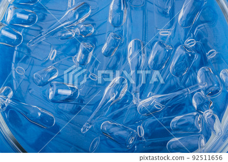 Glass medical ampoule vial for injection. Medicine is liquid sodium chloride with of aqueous solution in ampulla. Close up. Bottles ampule multicolor. Glass medical ampoule vial for injection. Medicine is liquid sodium chloride with of aqueous solution in ampulla. Close up. Bottles ampule multicolor. 92511656
