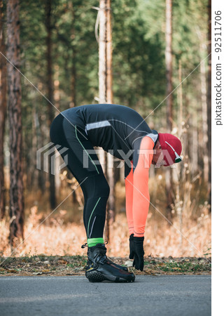 Training an athlete on the roller skaters. Biathlon ride on the roller skis with ski poles, in the helmet. Autumn workout. Roller sport. The athlete does the workout. Training an athlete on the roller skaters. Biathlon ride on the roller skis with ski poles, in the helmet. Autumn workout. Roller sport. The athlete does the workout. 92511706