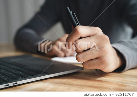 businessman holding pen by left hand working with laptop at office. businessman holding pen by left hand working with laptop at office. 92511707