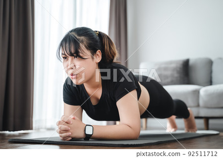 Asian chubby young woman doing planking exercise indoors at home .. Asian chubby young woman doing planking exercise indoors at home .. 92511712