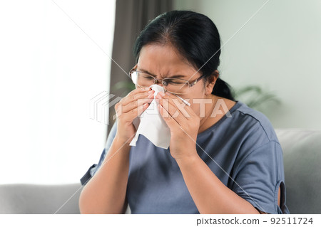 Cold sick woman got nose allergy cough or sneeze with tissue paper sitting on the sofa. Healthcare and medical concept.. 92511724