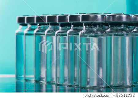 Glass medical ampoule vial for injection. Medicine is liquid sodium chloride with of aqueous solution in ampulla. Close up. Bottles ampule multicolor. 92511738